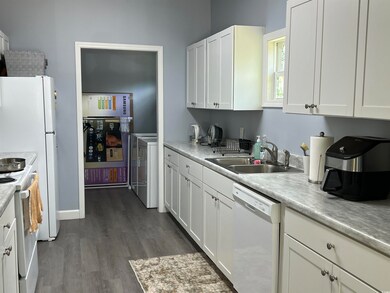 Kitchen with white appliances, white cabinetry, light countertops, and dark wood finished floors