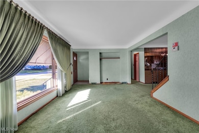 Unfurnished living room featuring carpet and baseboards