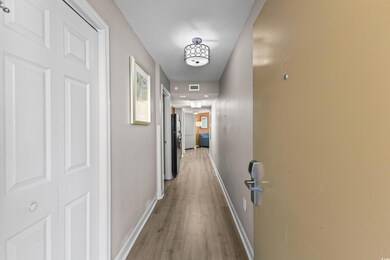 Hallway featuring a textured ceiling, light wood-s