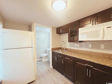 Kitchen with white appliances, a sink, backsplash,