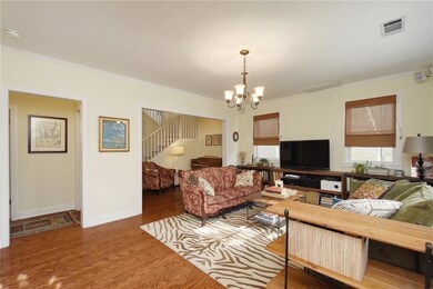 Living room with wood finished floors, ornamental molding, a chandelier, and stairs