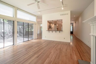 Unfurnished living room featuring wood finished floors, a ceiling fan, rail lighting, and baseboards