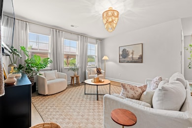 Living room with baseboards, healthy amount of natural light, a chandelier, and wood finished floors