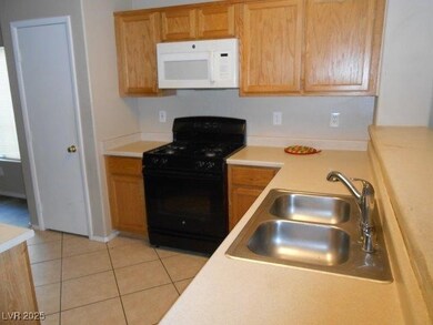 Kitchen featuring light countertops, gas stove, white microwave, and light tile patterned flooring
