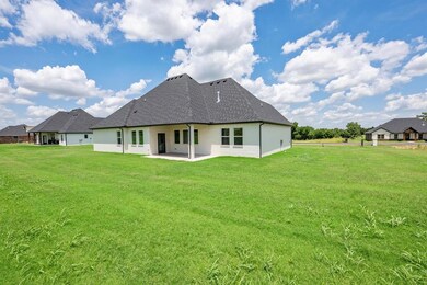 Rear view of house with a shingled roof, a patio area, and a yard