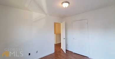 Unfurnished bedroom with wood finished floors, a closet, and baseboards