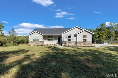 View of front of property with stone siding, covered porch, and a front yard