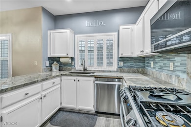 Kitchen featuring stainless steel appliances, white cabinets, quartz counters and tiled backsplash