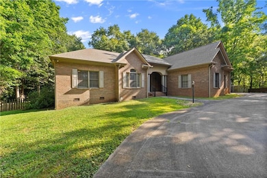 View of front of property featuring crawl space, brick siding, roof with shingles, and driveway