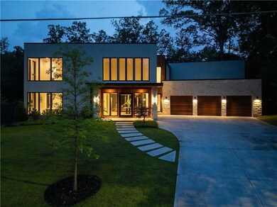 Contemporary home featuring driveway, stone siding, a front lawn, and an attached garage