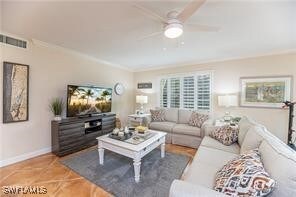 Living room with crown molding, ceiling fan, and t