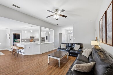 Living room featuring arched walkways, light wood-style flooring, a chandelier, and ceiling fan