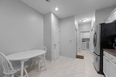 Kitchen with washer / dryer, light marble finish flooring, freestanding refrigerator, dark countertops, and baseboards
