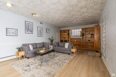 Living room with visible vents, wood finished floors, and a baseboard heating unit