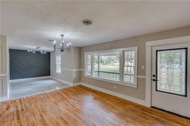 Unfurnished dining area with light wood-style flooring, a chandelier, and a textured ceiling