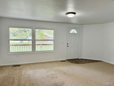 Entryway with a textured ceiling and light carpet