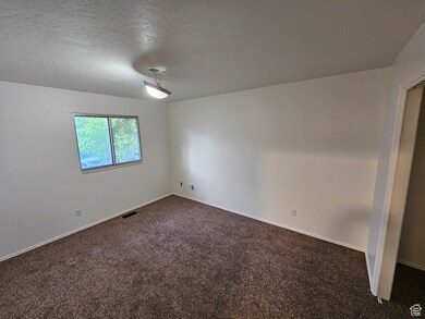 Spare room featuring dark carpet and a textured ceiling