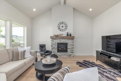 Living room featuring a stone fireplace, light wood-type flooring, high vaulted ceiling, recessed lighting, and beamed ceiling