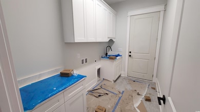Laundry area featuring hookup for an electric dryer, cabinet space, hookup for a washing machine, and baseboards
