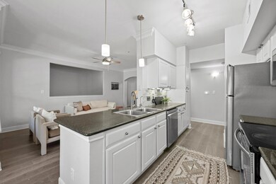 Kitchen with arched walkways, white cabinetry, ap