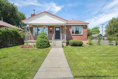 View of front facade featuring covered porch, brick siding, a chimney, and a tile roof