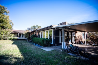 Back of property featuring a chimney, a yard, brick siding, and a sunroom