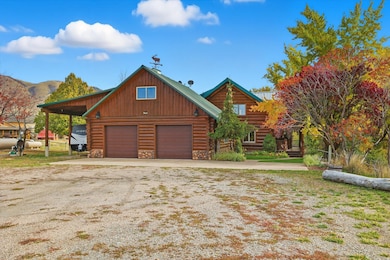 Log cabin featuring log exterior, a carport, a garage, and stone siding
