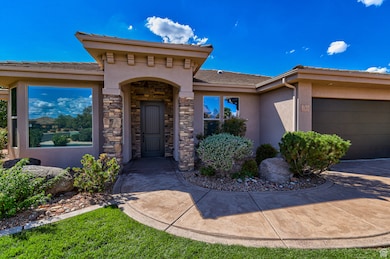 Property entrance featuring stucco siding, stone siding, a garage, and driveway