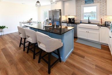 Kitchen with appliances with stainless steel finishes, a sink, wood finished floors, and white cabinetry