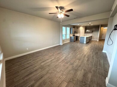 Unfurnished living room featuring ceiling fan, dark hardwood / wood-style flooring, and sink