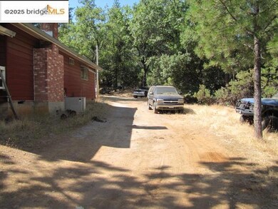View of side of property with a chimney, crawl space, driveway, and a view of trees