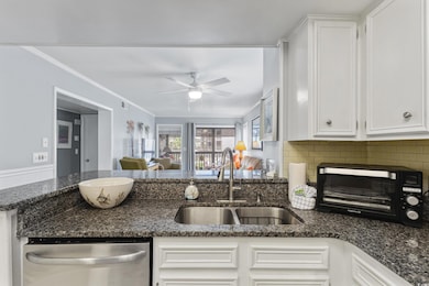 Kitchen featuring a sink, stainless steel dishwasher, a ceiling fan, white cabinets, and crown molding