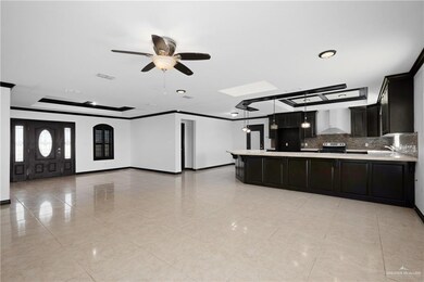 Kitchen featuring light tile floors, ceiling fan, tasteful backsplash, crown molding, and wall chimney exhaust hood