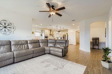 Living room with arched walkways, light wood-type flooring, a ceiling fan, and recessed lighting