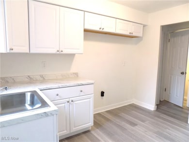 Kitchen with white cabinetry, light countertops, and LVT flooring