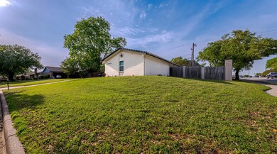 View of side of home with a yard, fence, and brick
