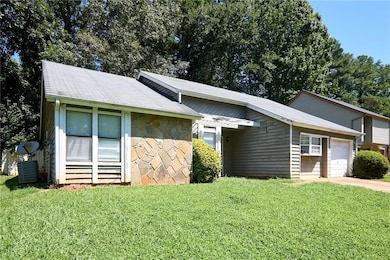 View of front of property featuring a front lawn, stone siding, a garage, and driveway