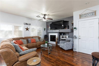 Living area featuring wood finished floors, a glass covered fireplace, and a ceiling fan