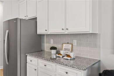 Kitchen with white cabinets, light stone counterto
