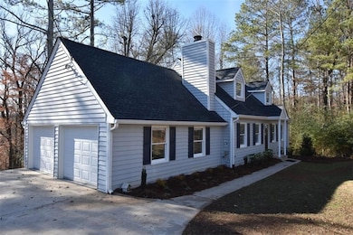 View of side of property with a chimney, a garage, and a shingled roof