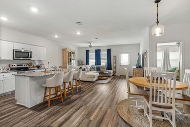 Kitchen with appliances with stainless steel finishes, ceiling fan, dark wood-style flooring, white cabinetry, and backsplash