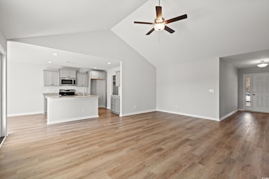 Unfurnished living room featuring light wood-style floors, a ceiling fan, high vaulted ceiling