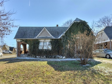View of front of property featuring a front lawn and a shingled roof