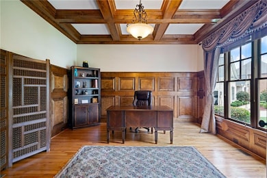 Home office featuring wainscoting, light wood-style flooring, beam ceiling, coffered ceiling, and ornamental molding