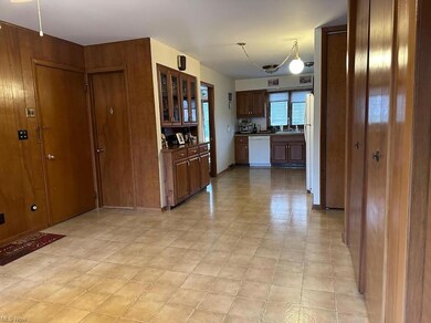 Kitchen with white dishwasher, dark brown cabinets, dark countertops, and light tile floors