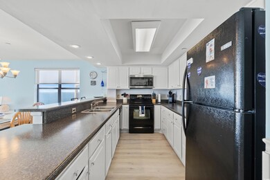 Kitchen with white cabinetry, a tray ceiling, sink