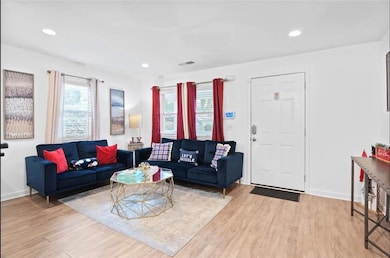 Living area with light wood-type flooring, baseboards, and recessed lighting