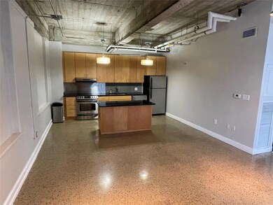 Kitchen featuring stainless steel appliances, dark countertops, a center island, under cabinet range hood, and hanging light fixtures