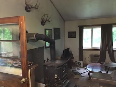 Bedroom featuring lofted ceiling, a wall mounted air conditioner, and a wood stove
