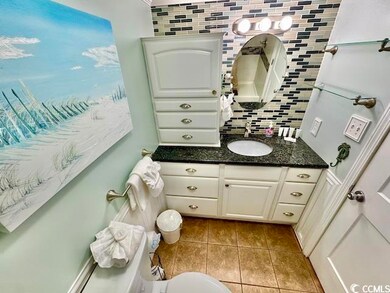 Bathroom featuring vanity, tile patterned flooring, tasteful backsplash, and toilet